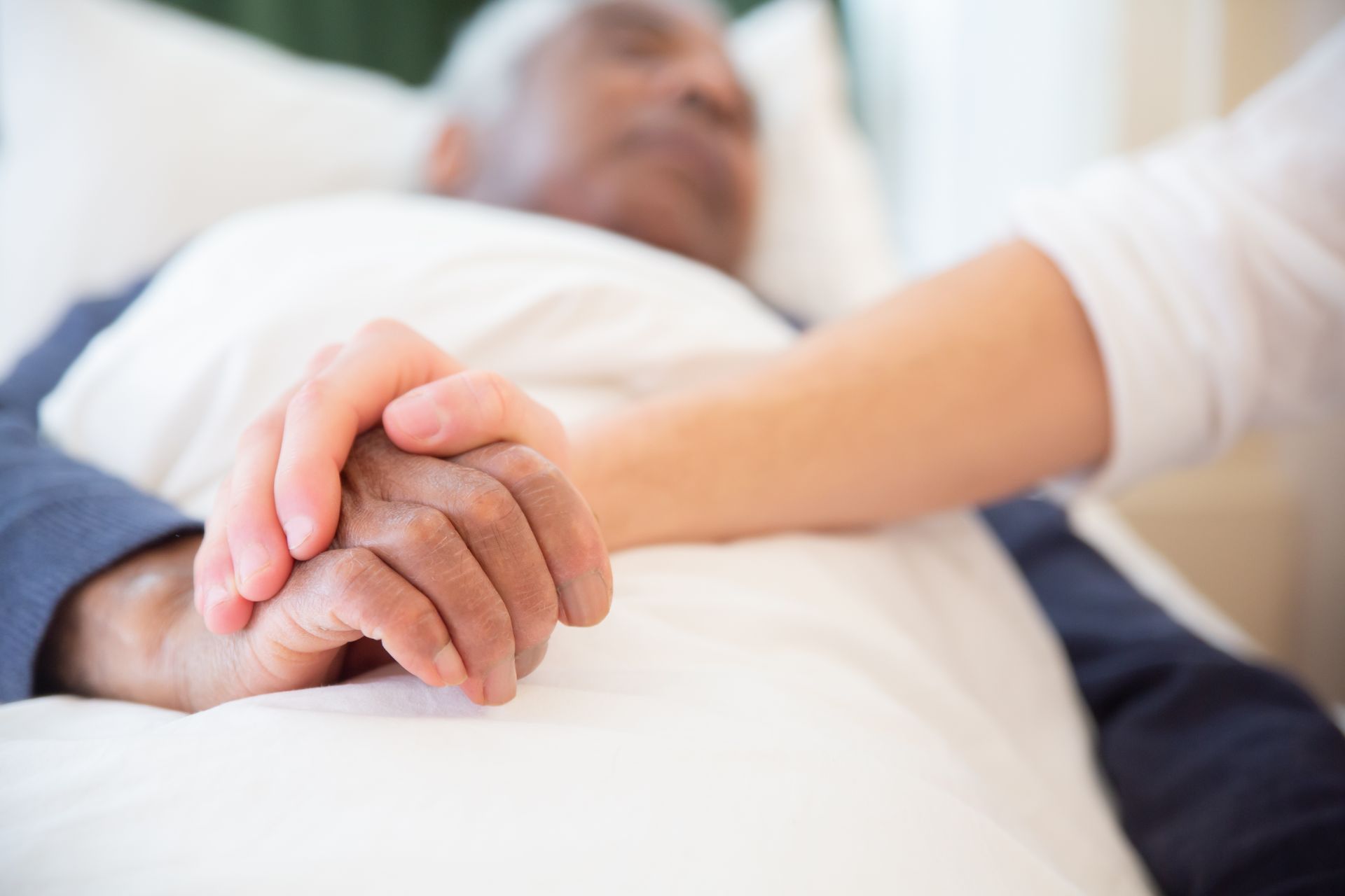 Mains entrelacées d'une aidante à domicile et d'une personne âgée